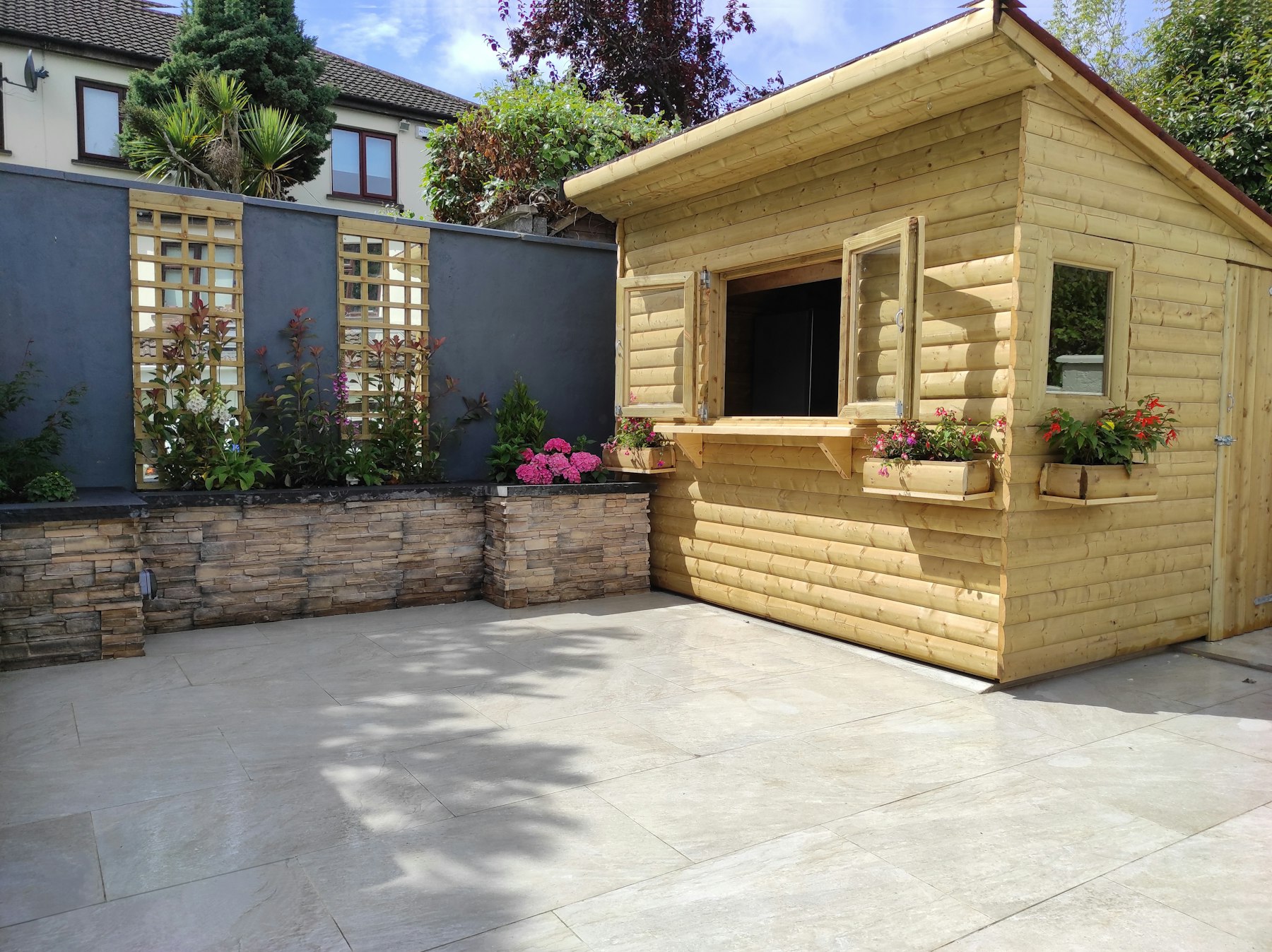 Clean pale paving slabs beside a garden cabin after pressure washing